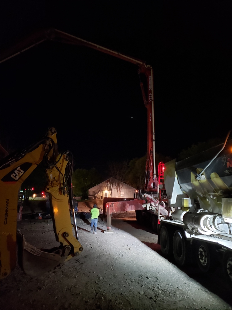 Cocnrete pump truck boom extending over job-site.